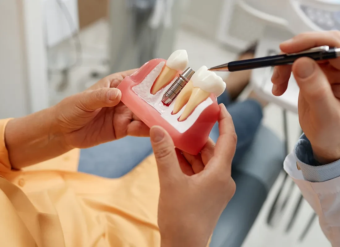 A dentist explaining treatment with a dental model